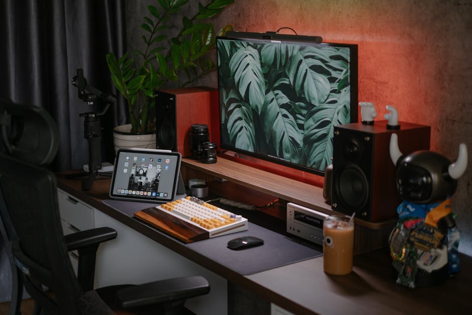 A stylish home office setup featuring a monitor, tablet, speakers, and decorative items. Ideal for tech enthusiasts.